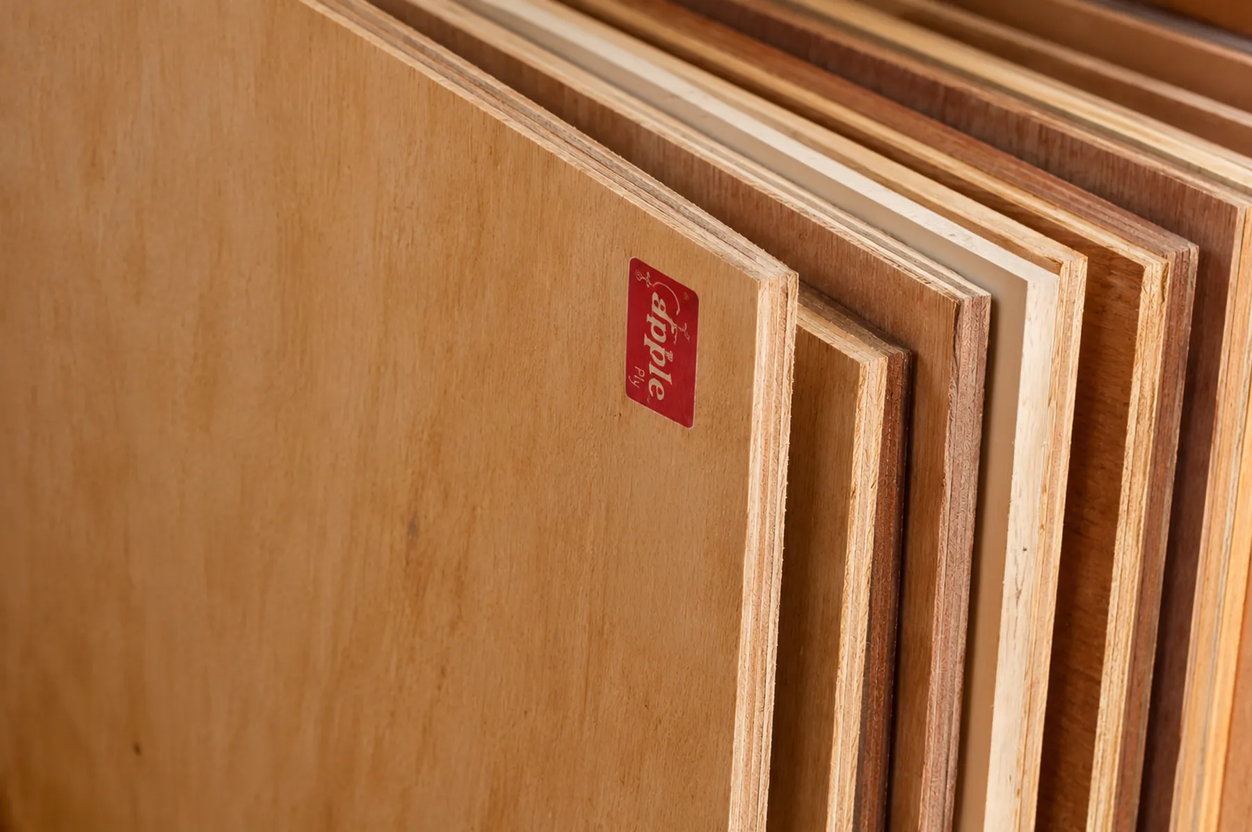 Close-up of stacked birch plywood sheets with an AK Apple Ply label
